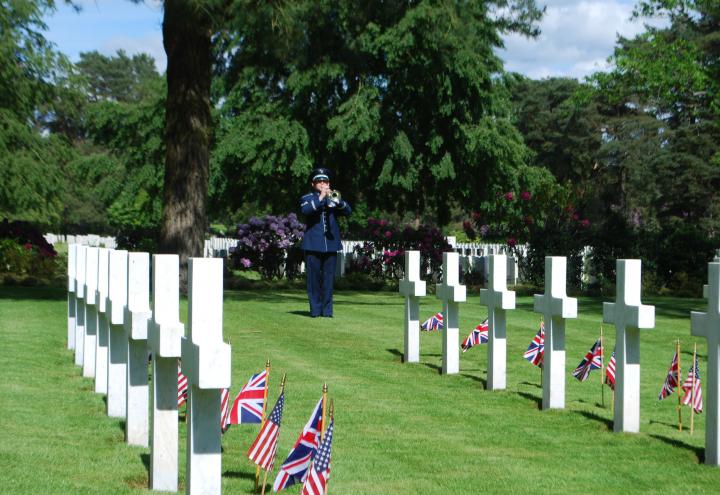 A bugler stands amongst the headstones and plays. 