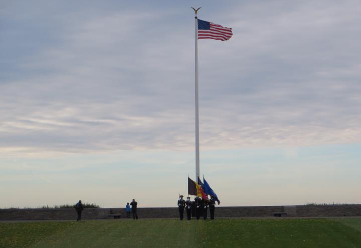 In the distance, an honor guard is seen at the flag pole. 