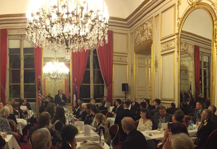 Attendees sit in an ornate room during John Wessel's speech