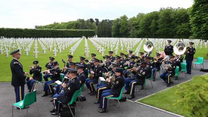 Men and women in uniform sit while they play their instruments. 