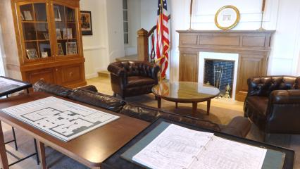 A fireplace, leather furniture, a large wooden cabinet and tables fill the entrance area of the visitor center. 