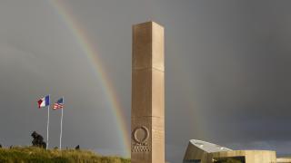 A double rainbow appears in the sky behind the memorial.