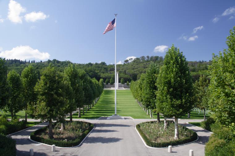 A flag pole, with the memorial building in the distance, at Florence American Cemetery. 