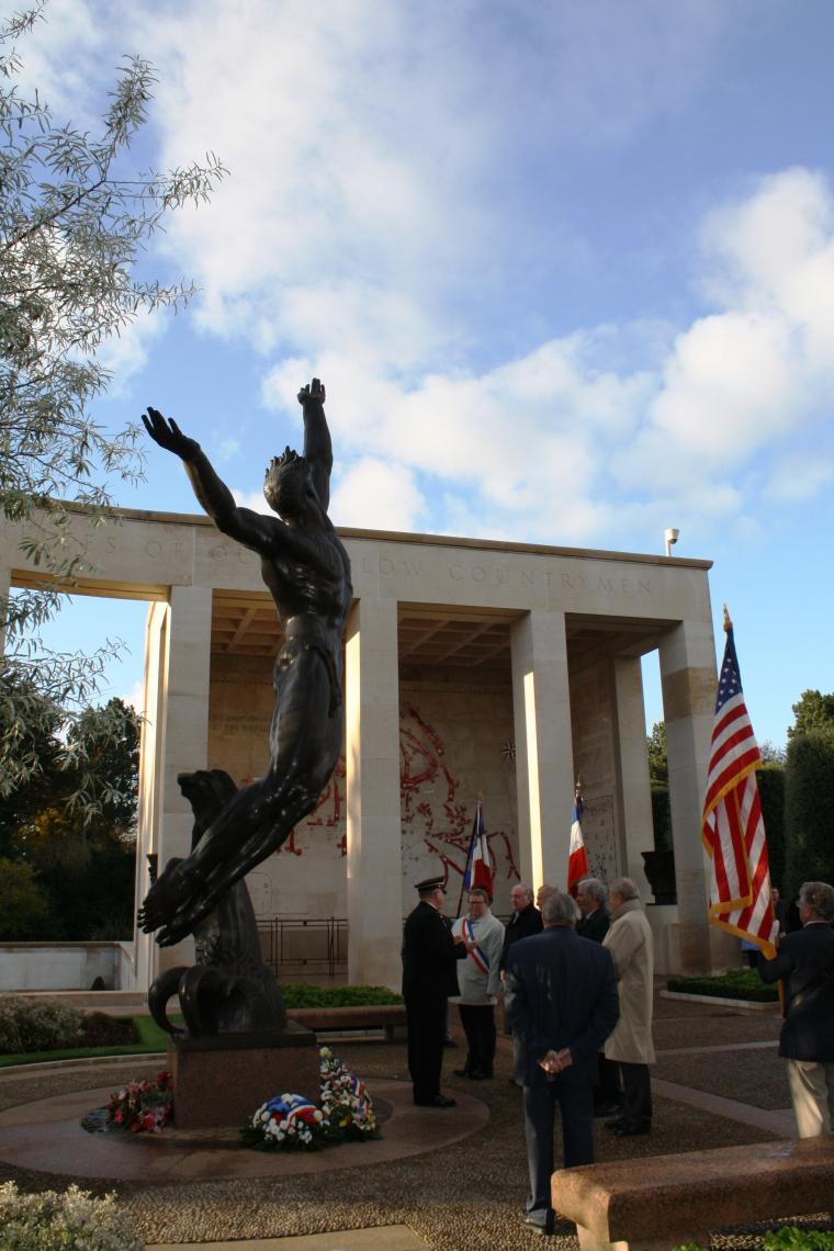 Wreaths lay at the base of a large statue at Normandy American Cemetery. 