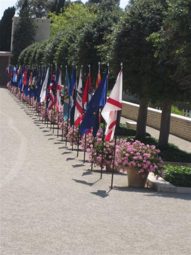 Large flags line a gravel path at the cemetery. 