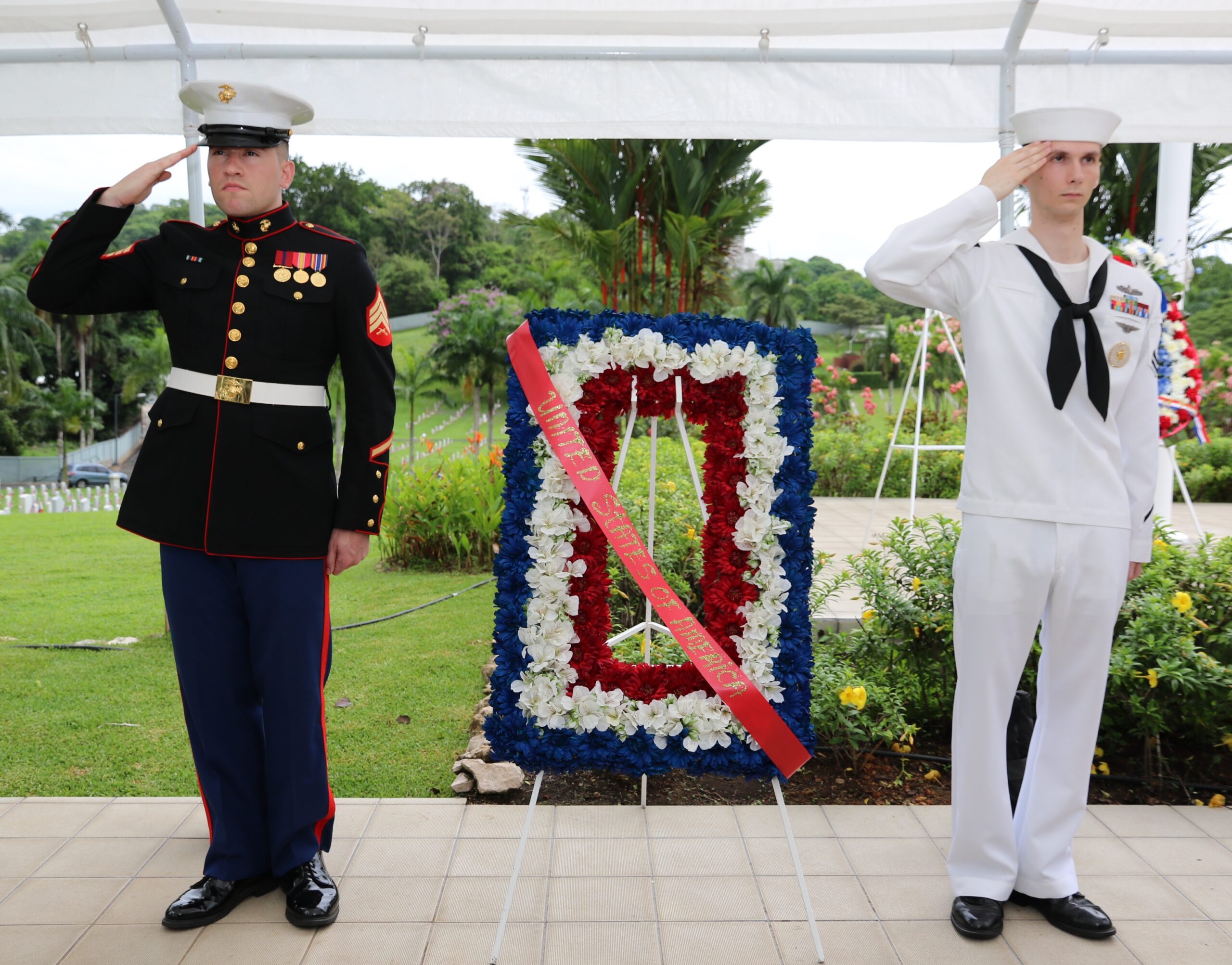 A Marine and a sailor salute after laying a floral wreath during the 2015 Memorial Day Ceremony at Corozal American Cemetery. Image courtesy of the U.S. Embassy Panama.