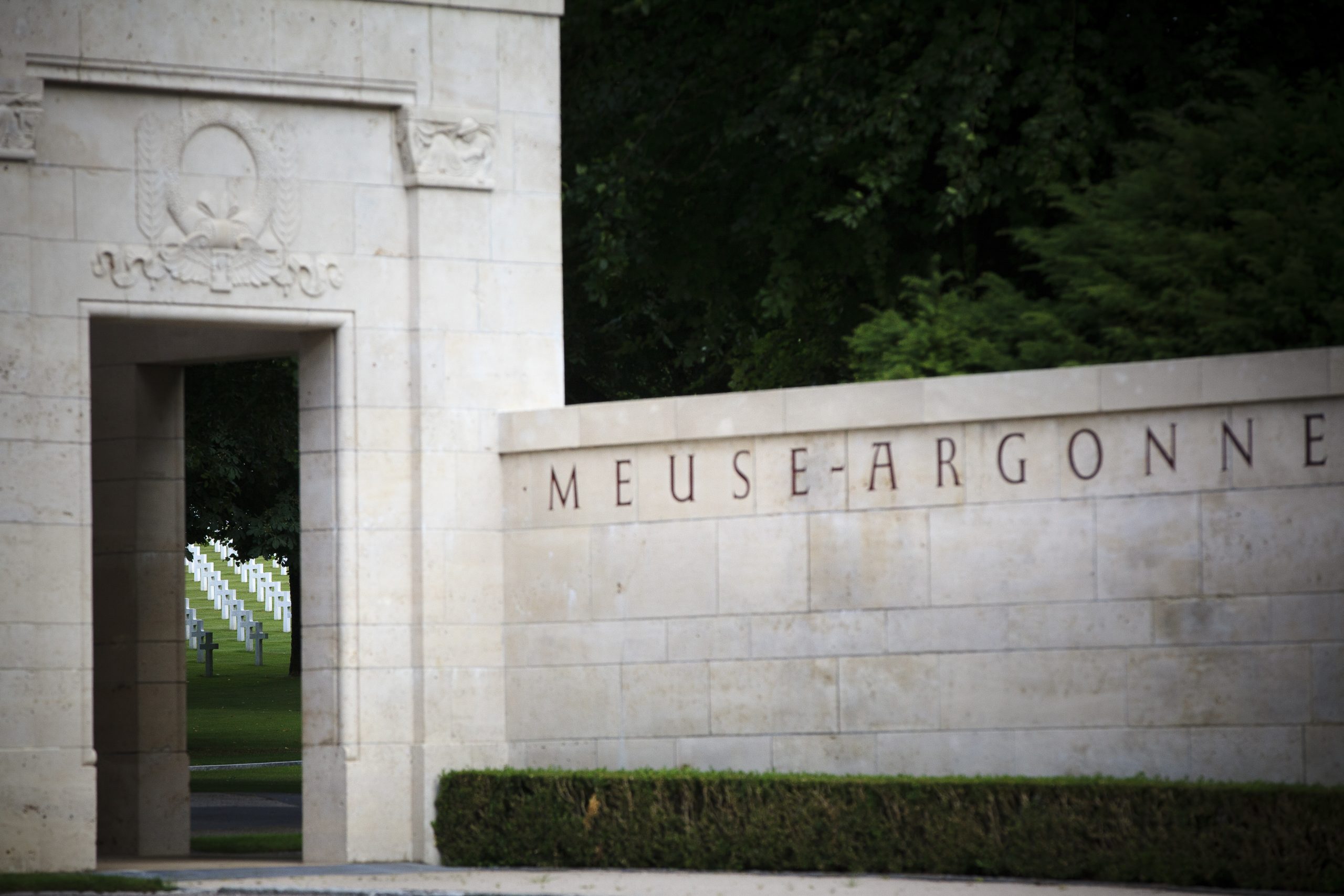 View of Meuse-Argonne American Cemetery wall entrance with a glimpse of the headstones in the back.