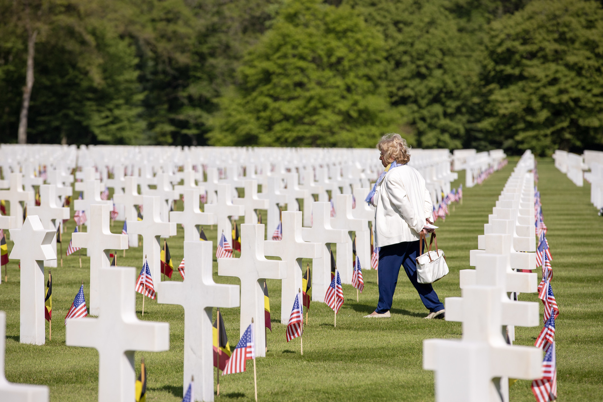 Person walking through rows of white headstones.