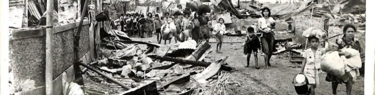 Filipino evacuees walk down a debris filled road to return to their homes after being freed by the 1st Cavalry Division.