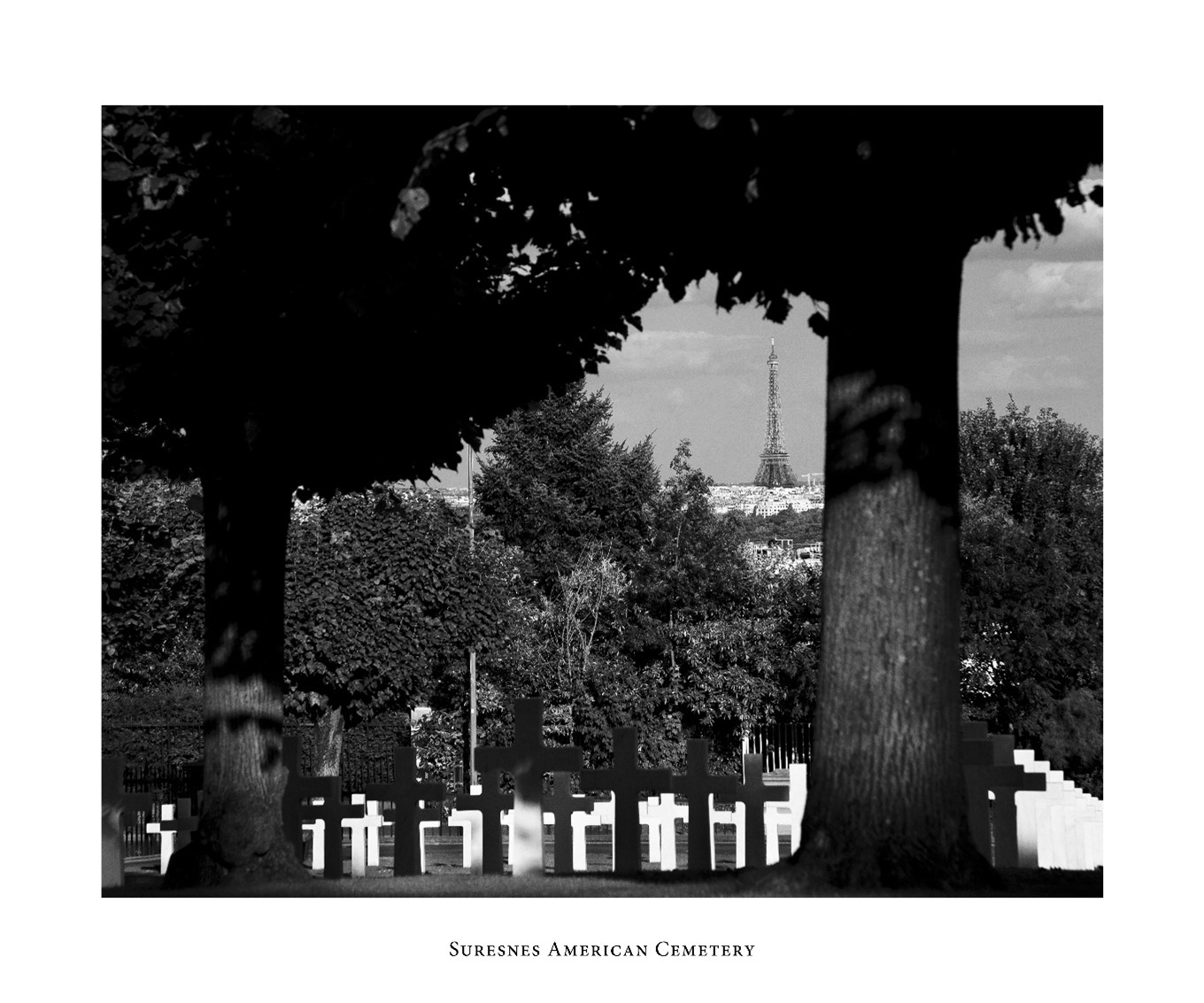 Black and white view of Suresnes American Cemetery with some headstones in the foreground and the Eiffel Tower from afar. Credits: American Battle Monuments Commission