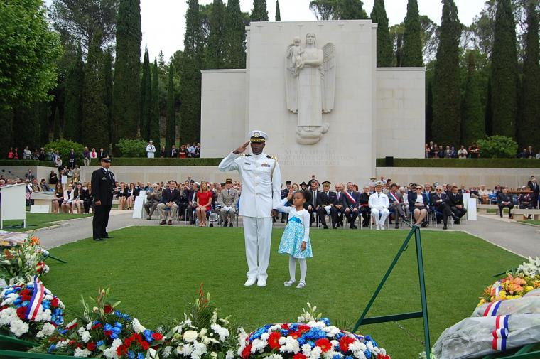 A father and daughter lay a floral wreath together during the 2014 Memorial Day Ceremony at Rhone American Cemetery.