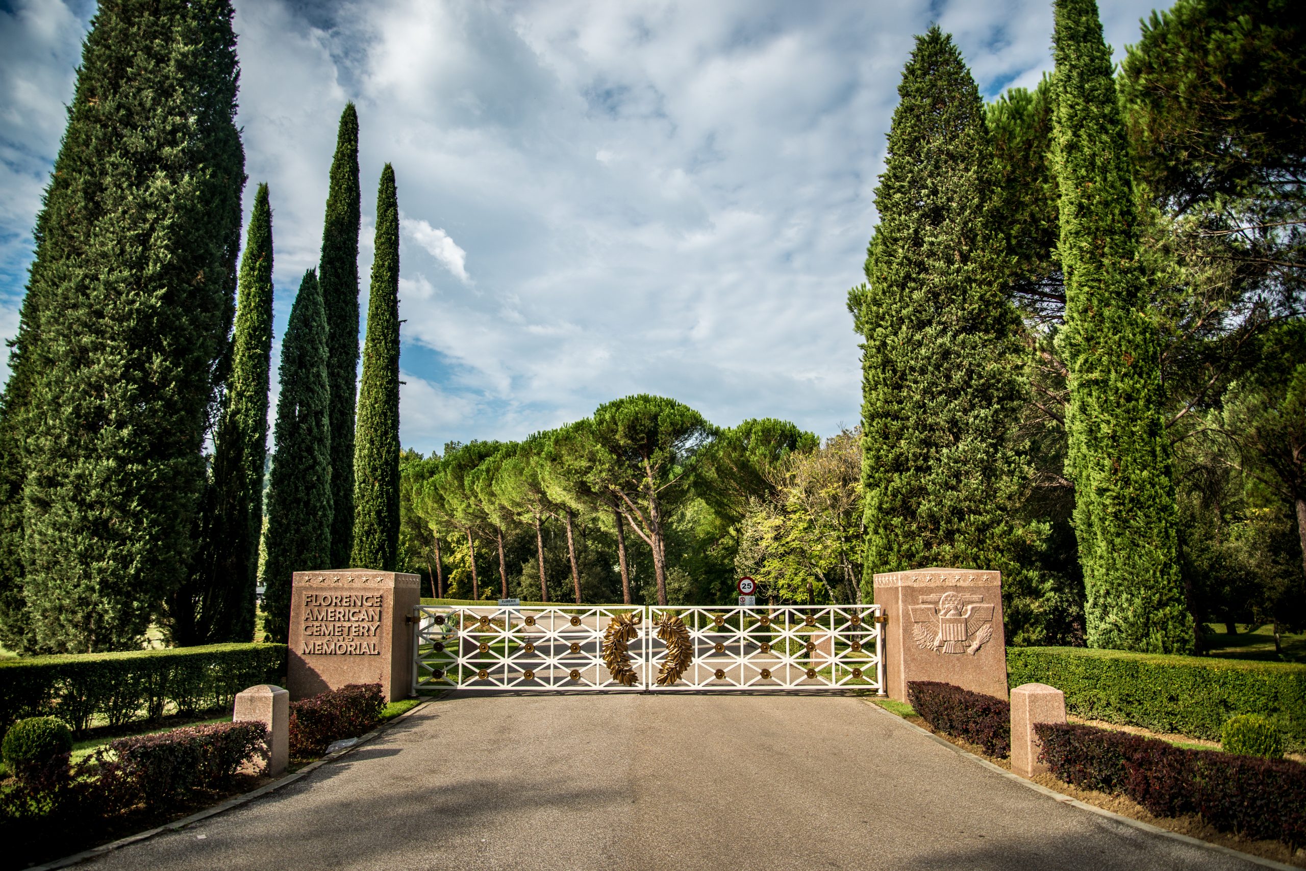 View of the entrance of Florence American Cemetery from across the bridge with the gate closed.