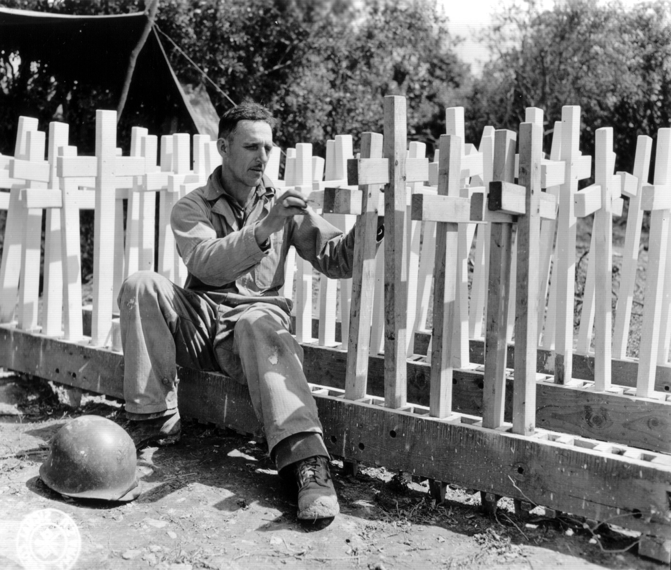 A man with the American Graves Registration Service prepares temporary grave markers.
