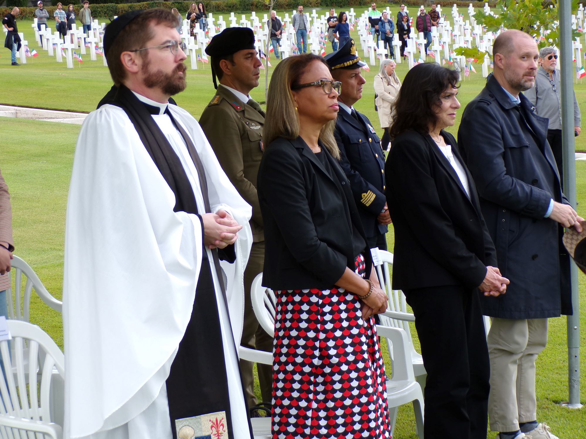 Be the Difference event Ceremony participants stand under a tent at the cemetery. In the background others stand beside headstones.