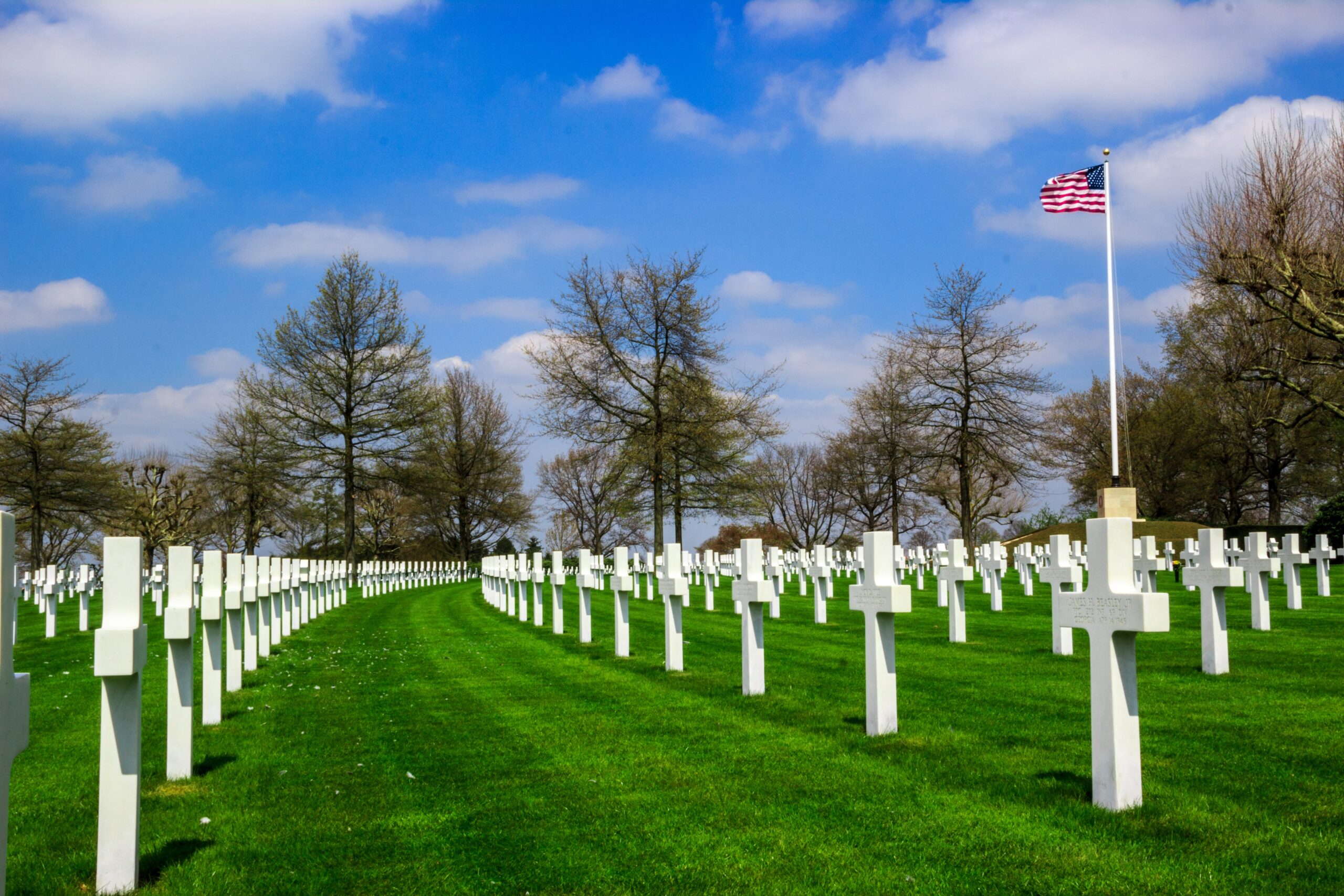 Green grass and white headstones cover the ground at Netherlands American Cemetery.