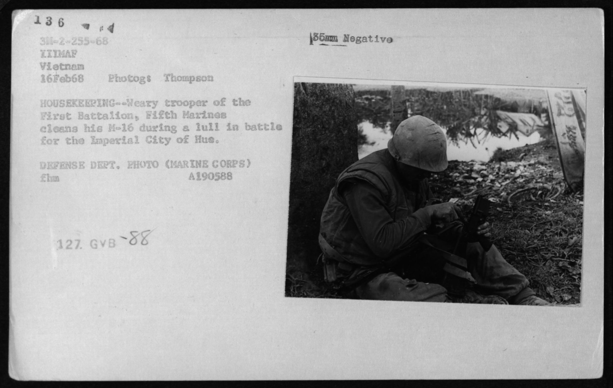 Black and white photo of a Marine cleaning his M-16 during a break in battle, February 16, 1968. National Archives and Records Administration (A190588).