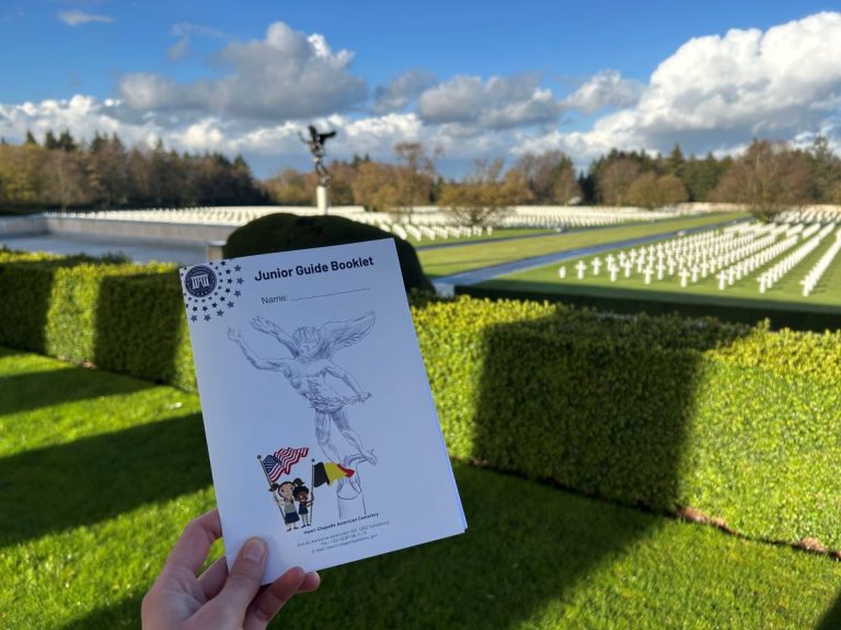 A guide at Henri-Chapelle American Cemetery in Belgium holds the Junior Guide booklet for their site. Each site-specific booklet includes activities tailored specifically for children to engage them in learning about ABMC and the stories of those commemorated there. (ABMC photo).