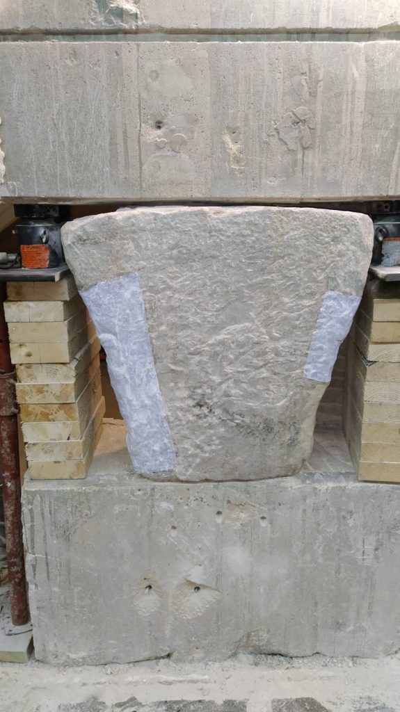 Close-up view of the Chateau-Thierry Bridge keystone after surrounding materials were removed to expose the stone. Protective patches and support cribbing are visible as conservators assess the artifact's condition before extraction.