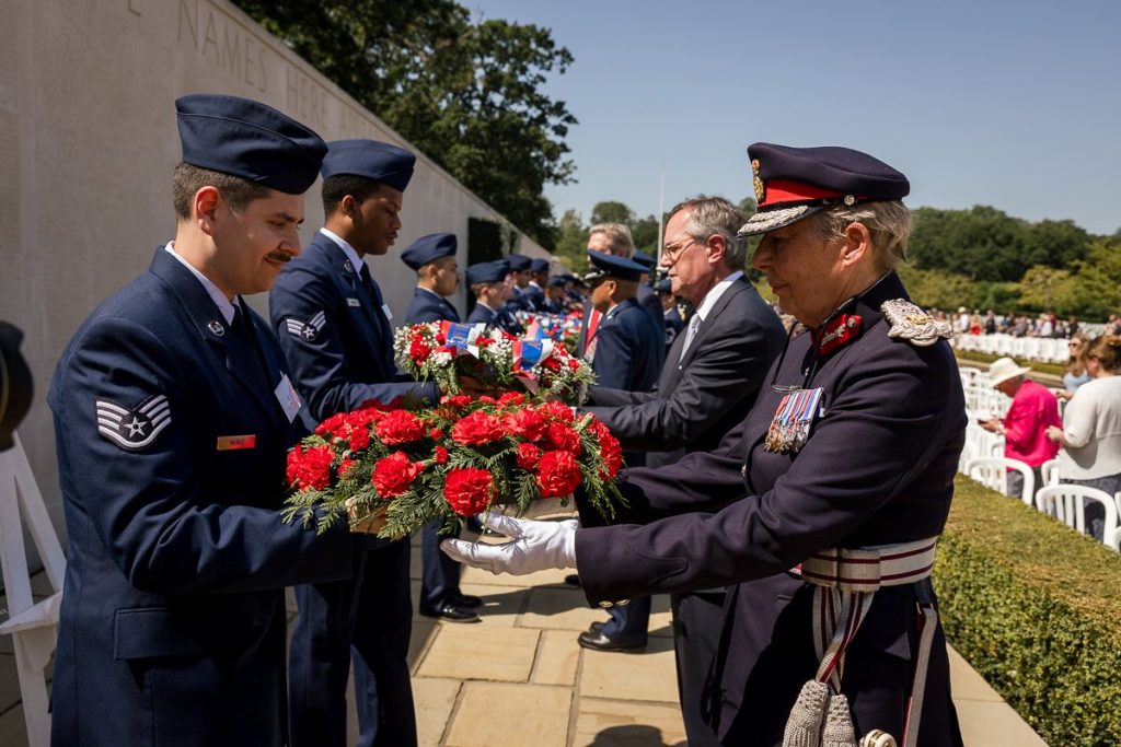 Wreath bearers from area U.S. Air Force bases pass more than 100 wreaths over to the presenters who laid them at the Walls of the Missing May 25, 2026, during the Memorial Day ceremony at Cambridge American Cemetery. (ABMC/Richard Howell)