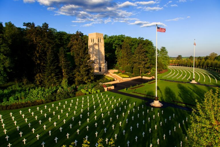 Aisne-Marne American Cemetery with the American Flag, headstones and chapel on a sunny day.