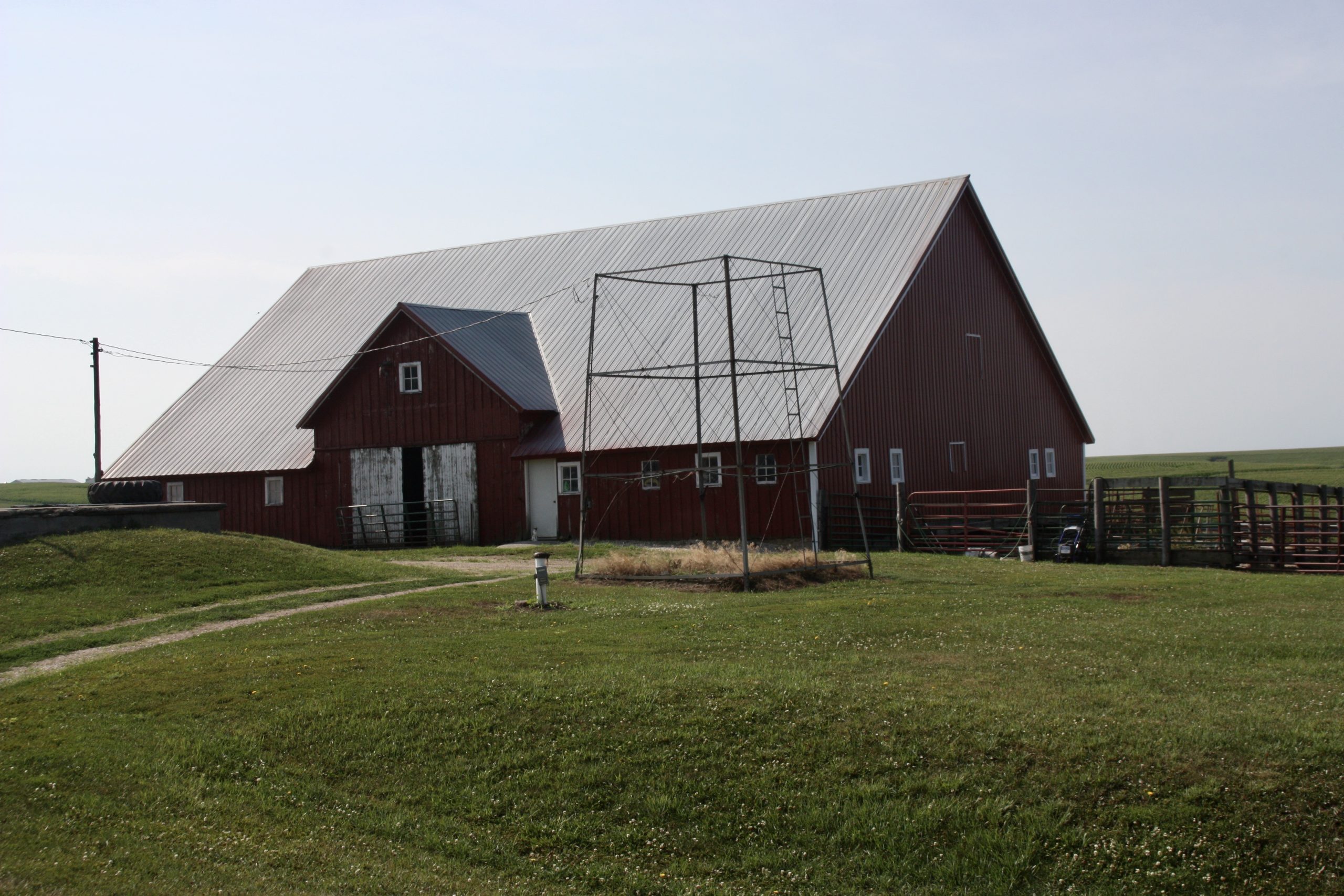 Large red farm barn with metal roof in grassy field.
