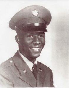 Portrait of a smiling young man wearing a formal military uniform and cap.
