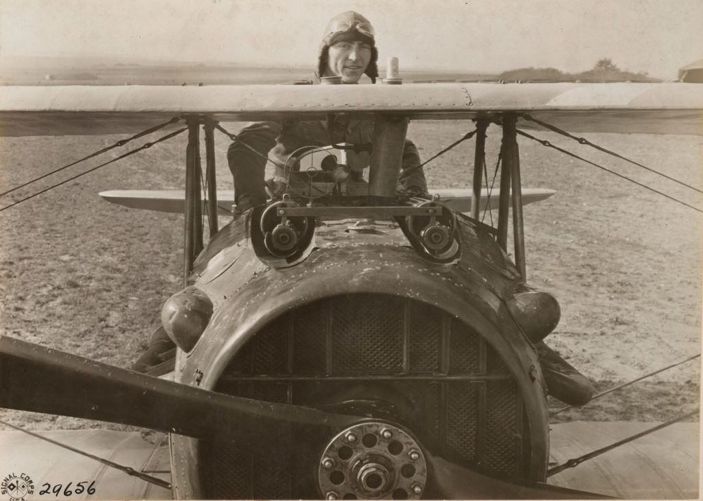 : First Lt. Eddie Rickenbacker standing in his aircraft. Rickenbacker visited Montsec and said observers could view aircraft above his airfield at Toul 16 kilometers southeast.