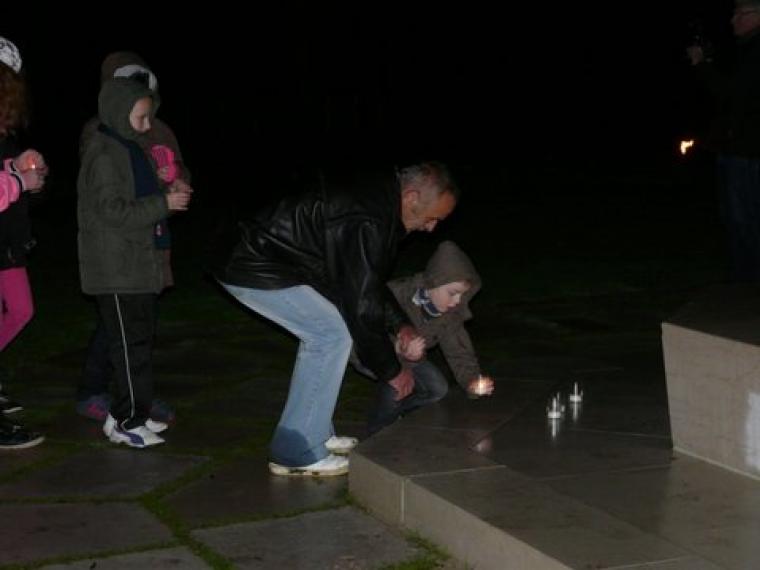 A man and a child participate in the La Flamme de la Mémoire Ceremony at Oise-Aisne American Cemetery.